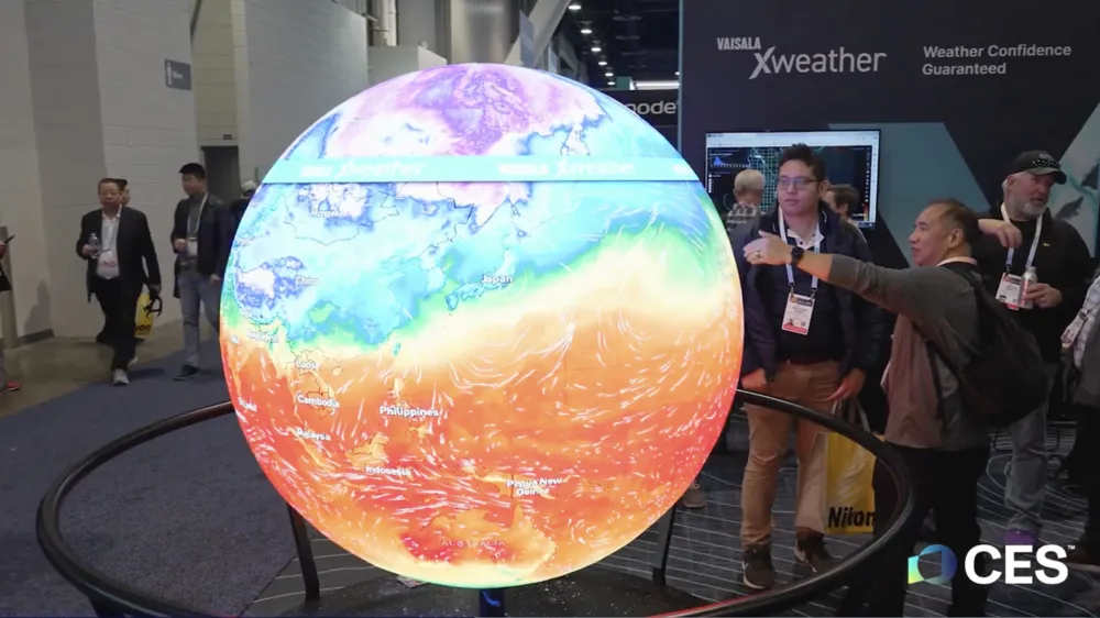 ALT Text: Attendees interact with a colorful, illuminated weather globe at the CES event