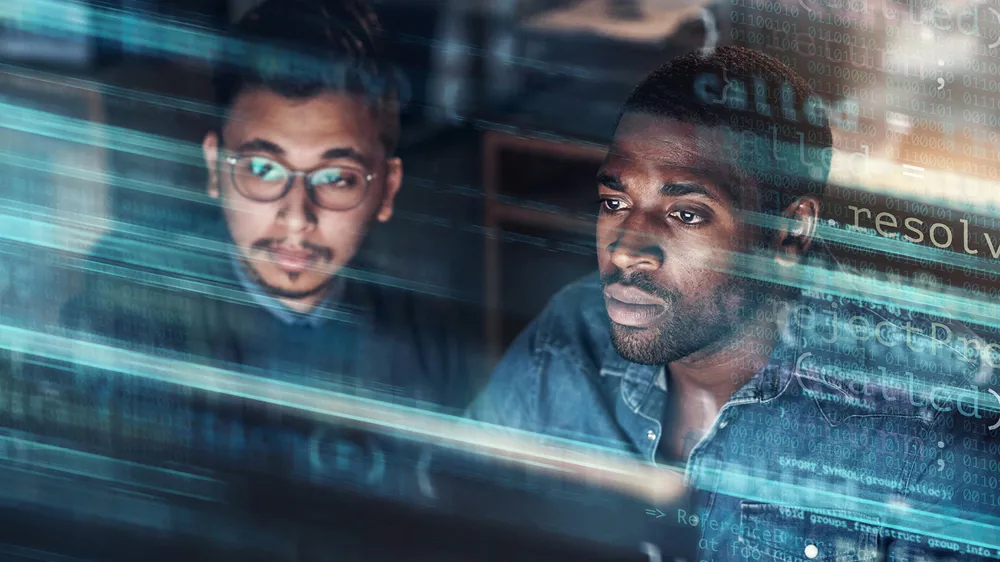 ALT Text: Two men looking at date and having the binary code floating Infront of them and out of the computer