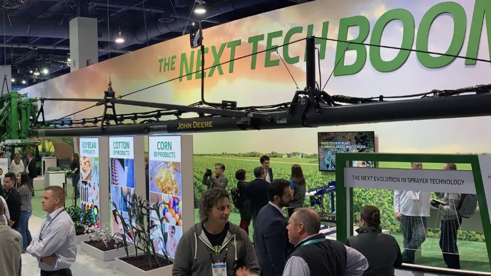 ALT Text: a panoramic view of John Deere's booth at CES with the banner saying the next tech BOOM